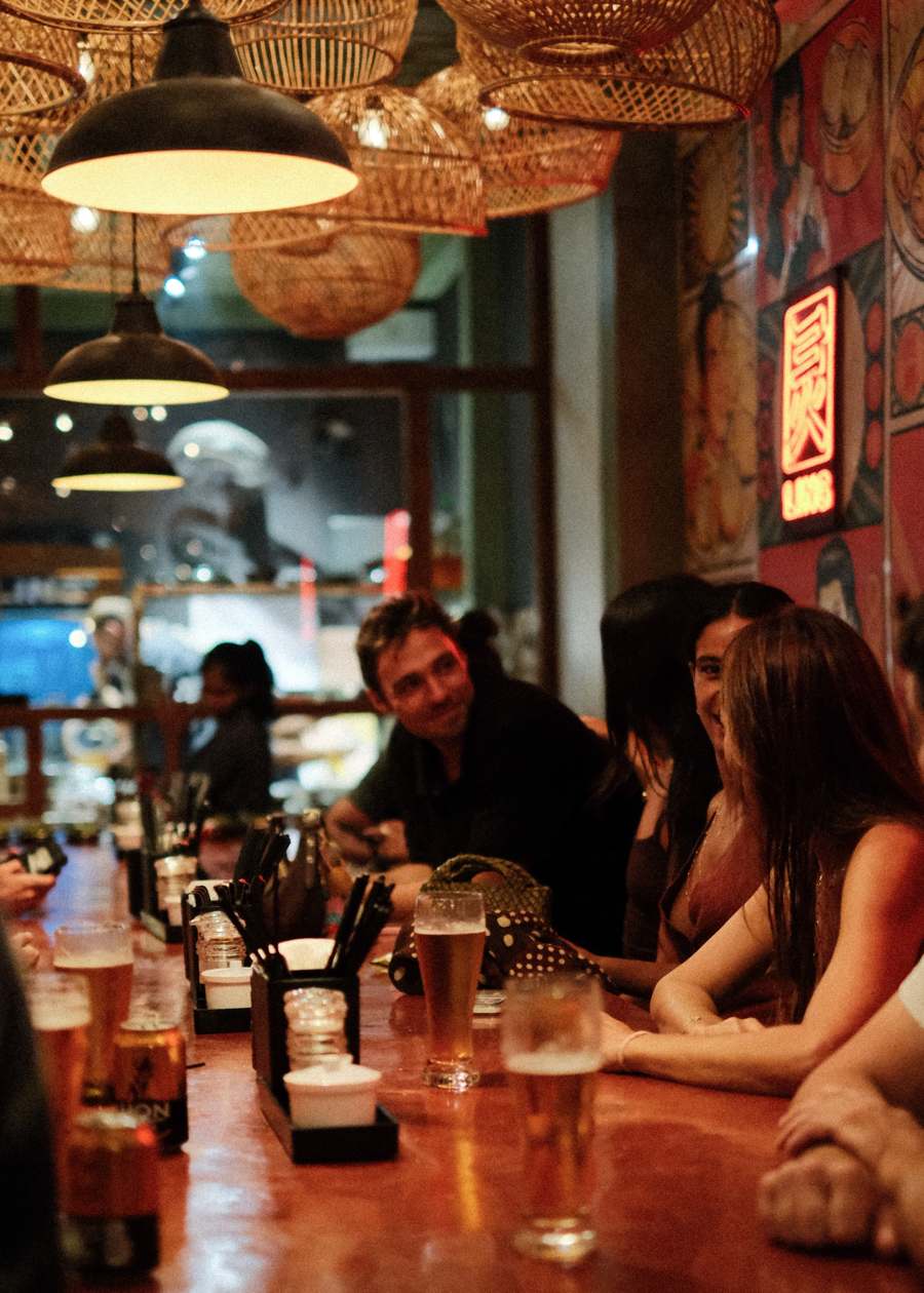 Guests along the bar under the lamps